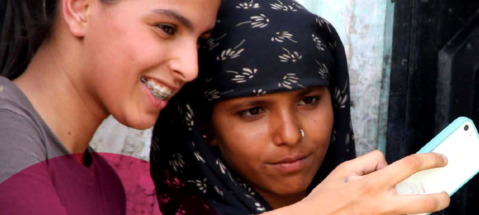 two young girls look at a smart phone.