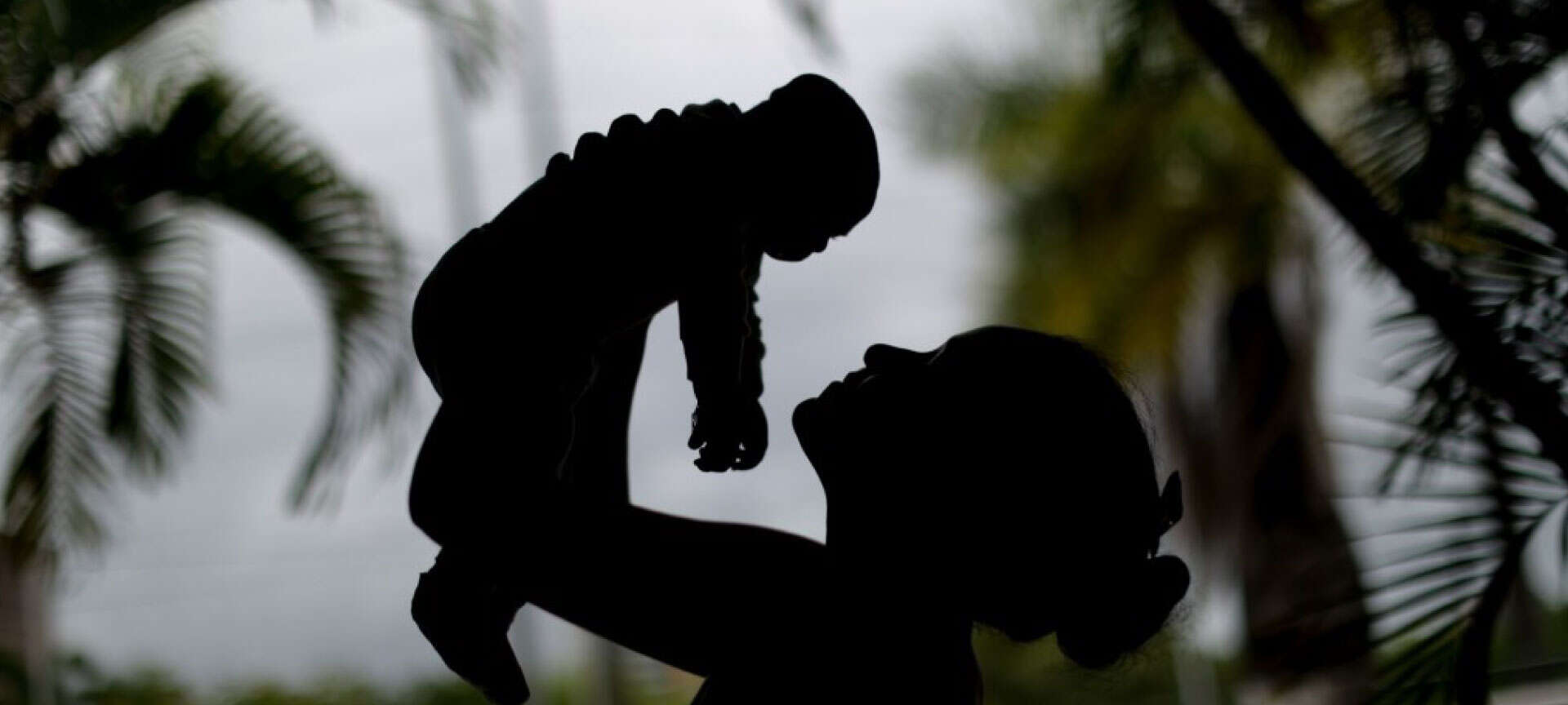 A silhouette of a mother holding up her infant child.