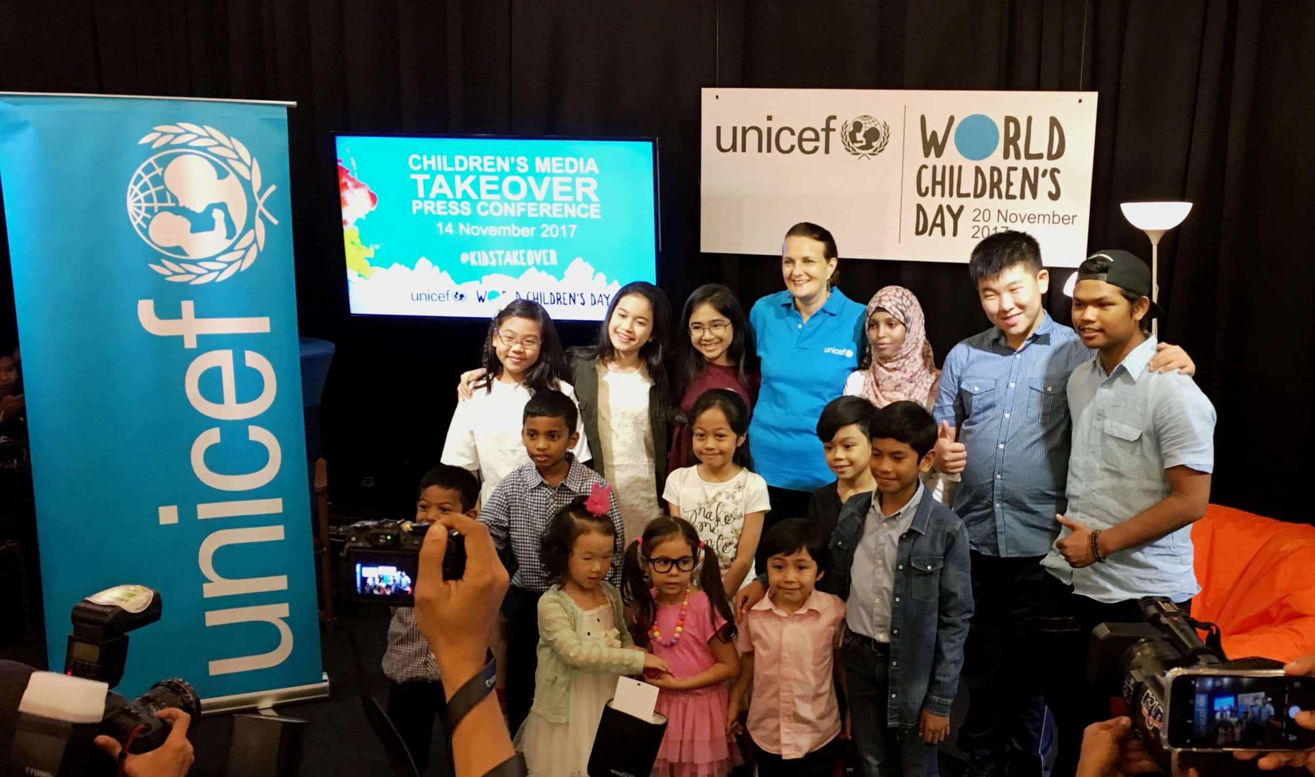 a group of children of different races and backgrounds stand together with UNICEF at the World Children's Day Kidstakeover Media in Malaysia press conference.