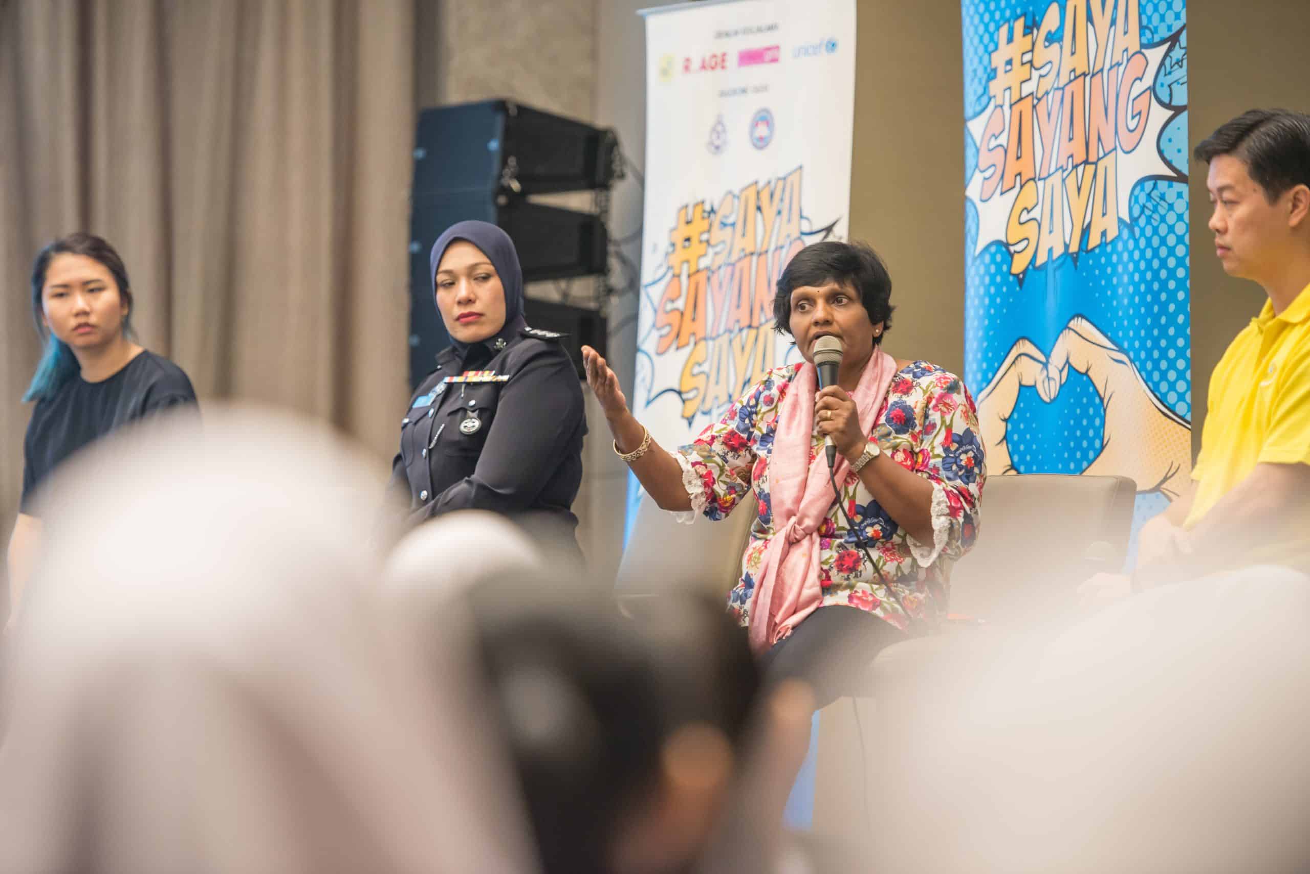 a panel of speakers on stage. Behind them are the Saya Sayang Saya buntings.