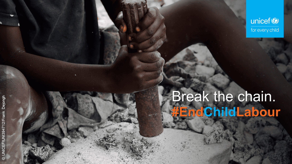 Hands of a boy holding an implement to break rocks and stones in a mine.