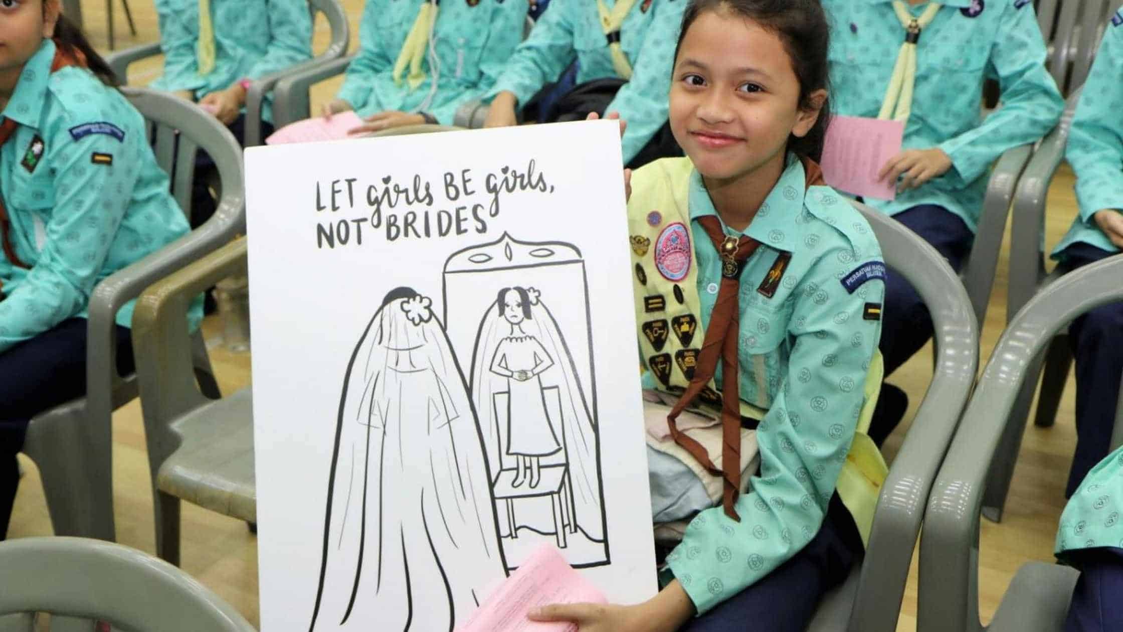 a girl guide holds up a poster to call for an end to child marriage