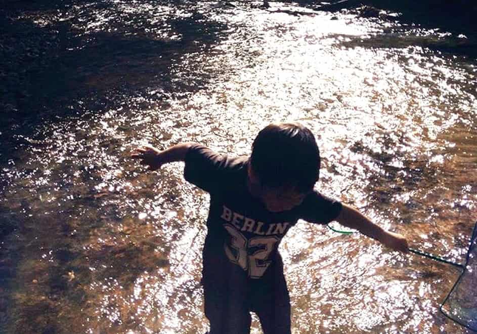 A YOUNG BOY HAVING FUN PLAYING IN A RIVER