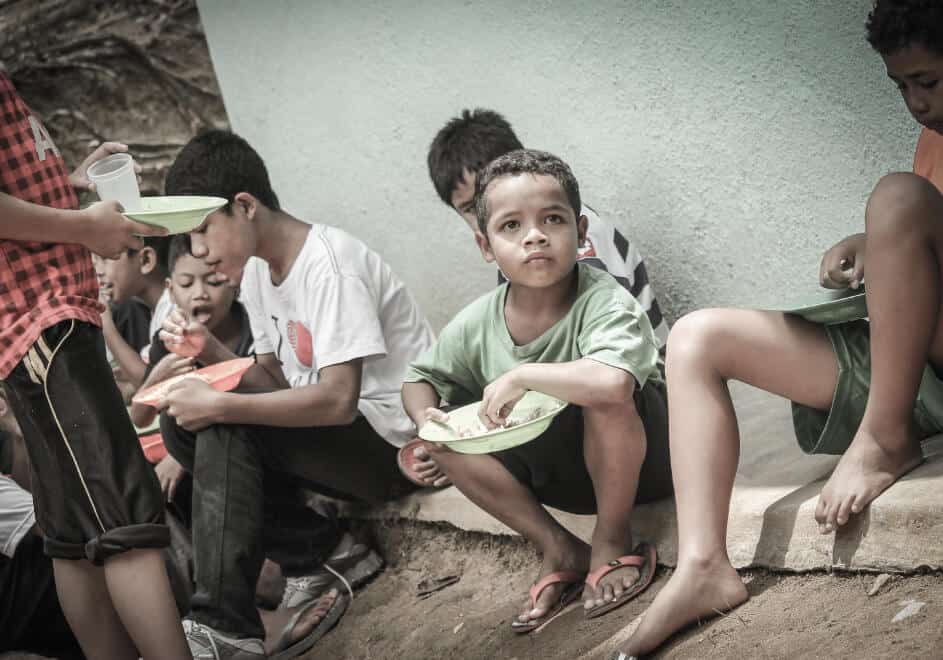 A GROUP OF YOUNG BOYS SITTING AND EATING