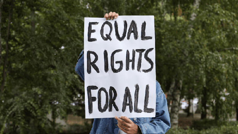 A young person holds up a sign that reads Equal Rights for All.