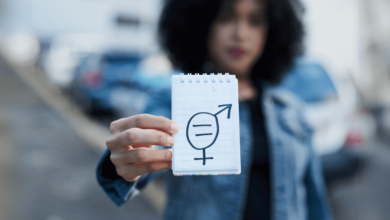 A young woman holds up a notepaper with gender symbols drawn on it to reject internalized misogyny.