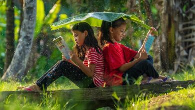 Two girls reading their books in the outdoors.