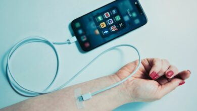 A phone showing social media icons connected to a woman's vein like a drip.