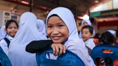 A smiling girl sitting in her classroom.