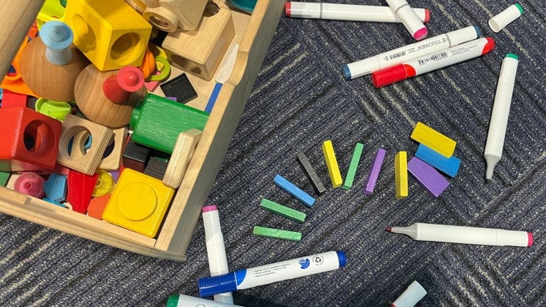 A group of toys and crayons on the floor.