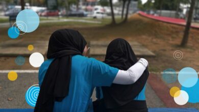 A young woman comforts her friend in the park.