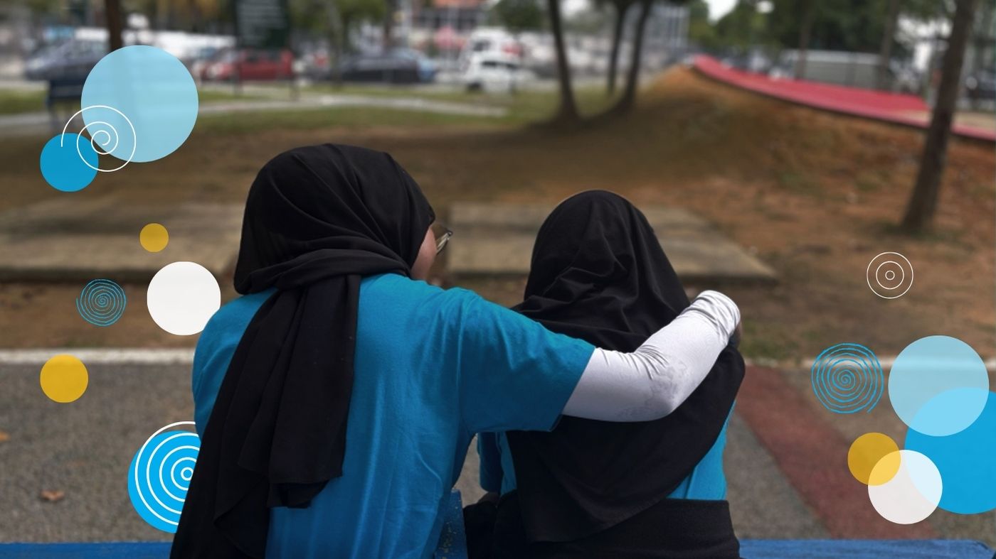A young woman comforts her friend in the park.