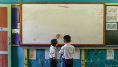 Two boys standing in front of a white board.