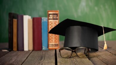 A graduation cap next to some stacked books.