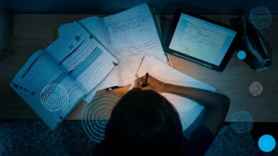 A young girl studying at her desk with school books around her.