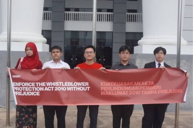 Five young people hold up a banner.