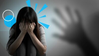 A scared woman sitting on the floor. A hand looms on the side.