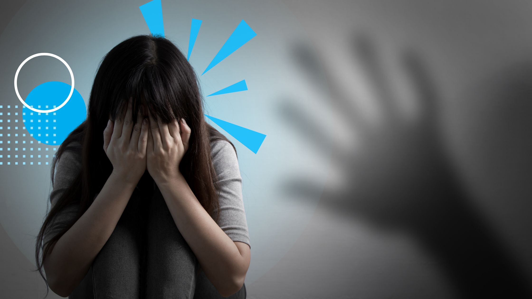 A scared woman sitting on the floor. A hand looms on the side.