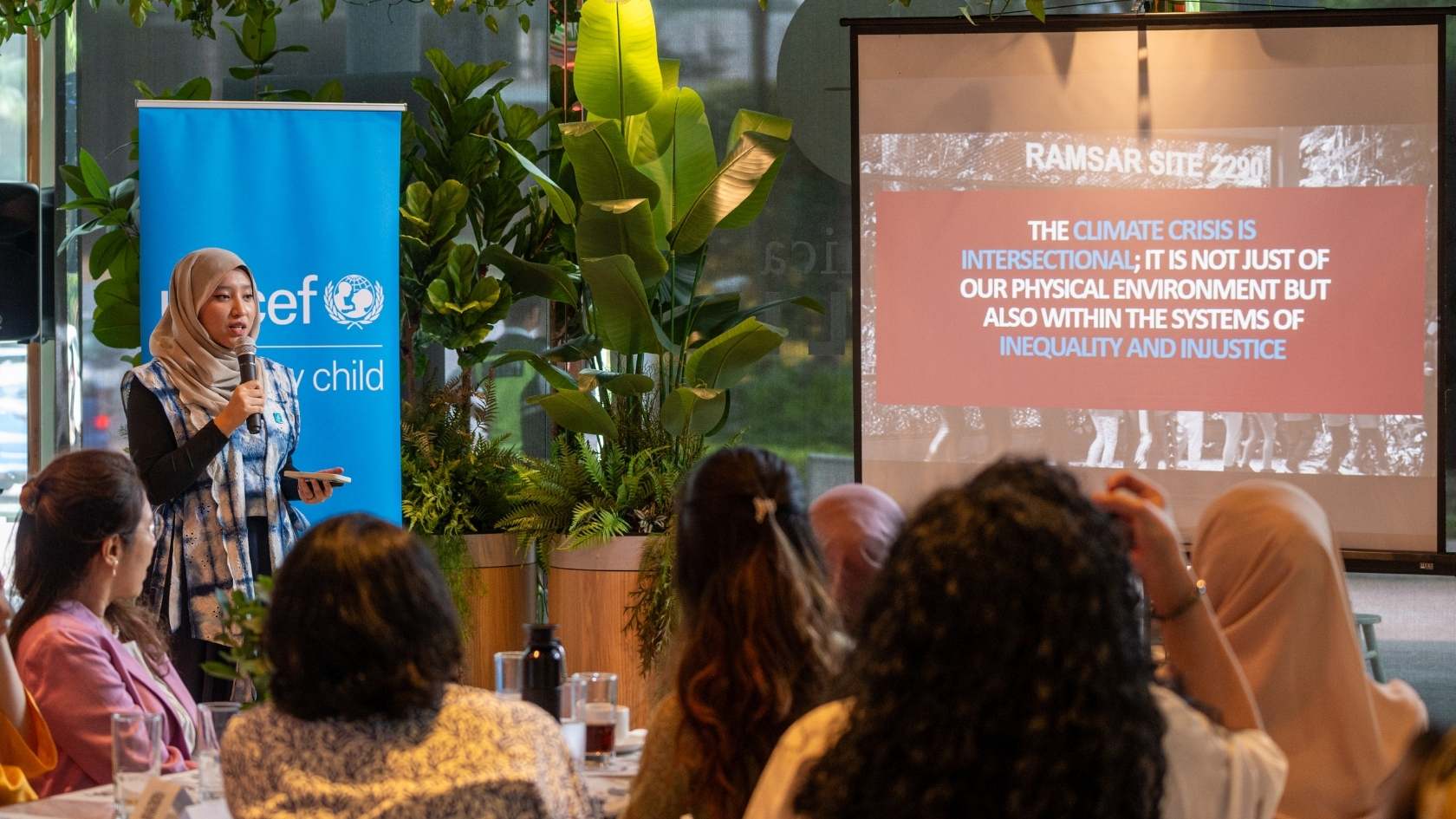 Young person speaking into a microphone during a climate and environment community event.